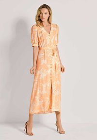Pfirsichfarbenes Blumenkleid mit Puffärmeln, V-Ausschnitt, Taillengurt und Knopfverschluss. Glattes Material mit dezentem Glanz, knielang.
