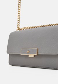 Borsa a spalla strutturata grigia realizzata in materiale testurizzato con tracolla in oro, dotata di una chiusura oro con un dettaglio del logo sul davanti.