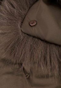 Chaqueta acolchada marrón con cuello de piel sintética, que presenta una textura suave y un detalle de un solo botón oscuro.