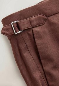 Brown denim pant waist with a silver metal buckle. Features a stitched texture and flat waistband design. Clean lines and minimal detailing.