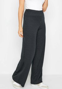 Brede broek in donker marineblauw met witte verticale strepen. De stof is zacht met een gladde textuur. Heeft een hoge tailleband en een ontspannen pasvorm.