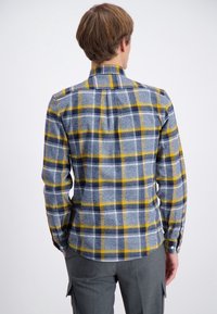 Overhemd met knoopsluiting in een blauw, geel en wit geruit patroon. Gemaakt van flanel, met een kraag en lange mouwen. Gestyled met een rechte zoom.