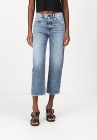 Jeans azzurri corti con design a gamba dritta, orli sfilacciati e cinque tasche, abbinati a sandali neri flat con doppia fibbia.