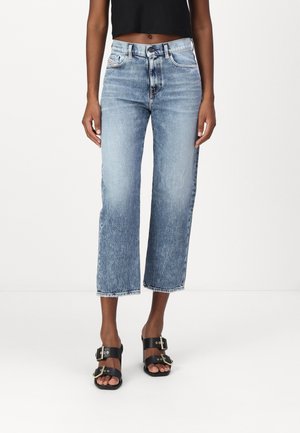 Ljusblå cropped jeans med rak bendesign, fransade fållar och fem fickor, parat med svarta platta sandaler med dubbla spännen.