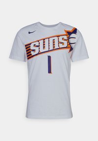 Vit Nike t-shirt med "SUNS" i fet lila och orange text samt en basketbollgrafik, rund hals och korta ärmar.