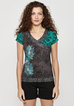 Haut noir à manches courtes avec des accents turquoise, en design col en V, broderie détaillée de fleurs et motif texturé le long de l'ourlet.