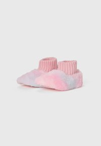 Une paire de chaussons moelleux, rose et lavande, avec des poignets en tricot côtelé sur un fond blanc uni.