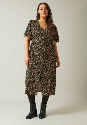 Kukkakirjailtu midi-mekko, jossa on lyhyet leijonasateen helmat, musta tausta, monivärisiä kukkia, V-pääntie ja röyhelöhelma; yhdistetty mustiin nilkkureihin.
