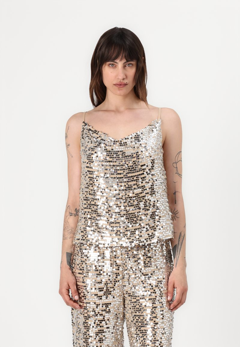 Silver and gold sequin camisole with thin straps, featuring a v-neckline and a loose fit, complemented by matching sequined pants.