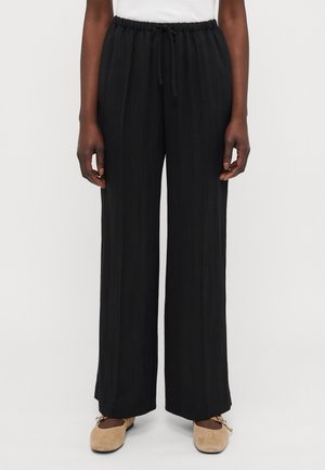 Black, wide-leg pants with an elastic waistband and drawstring. Made of lightweight fabric with a textured finish.