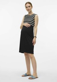 Maternity dress with a fitted black skirt and a striped upper. Made of soft fabric, featuring shoulder straps and a loose fit over the belly.