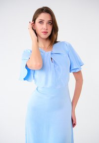 Hellblaues Kleid mit kurzen, fließenden Ärmeln und einem V-förmigen Ausschnitt, der an der Brust mit einem Knoten versehen ist, glatte Textur im gesamten Kleid.