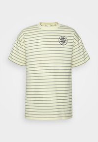 Gulrandig t-shirt med korta ärmar, som har en rund halsringning och en cirkulär logotyp med texten "Nike Athletic Club" på framsidan.