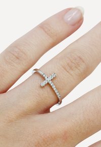 Silver band ring featuring a cross design adorned with clear, sparkling gemstones. The band is smooth, and the cross is slightly raised.