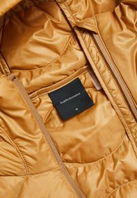 Gold insulated jacket interior with smooth, shiny fabric, visible zipper, and black label indicating brand and size "M."