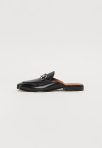 Melna ādas slip-on loafer ar nedaudz norādītu pirkstu, greznu sprādzi un zemu, kvadrātu papēdi. Gluda tekstūra un minimālistisks dizains.