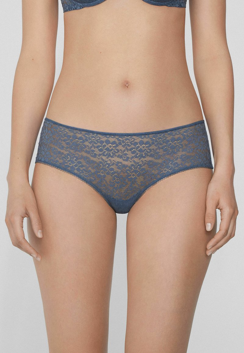 Krajkové kalhotky typu boyshort v tmavě modré barvě, zdobené květinovými vzory, hladkým pasem a vlnkovanými okraji. Lehké a poloprůhledné.