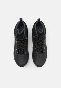 Zapatos de senderismo negros con parte superior de cuero y textil, que incluyen ojales de metal, punta redonda y un lazo en el talón para facilitar su colocación.