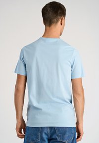 T-shirt di cotone celeste con maniche corte e scollo rotondo, caratterizzata da una texture liscia e un design minimalista.