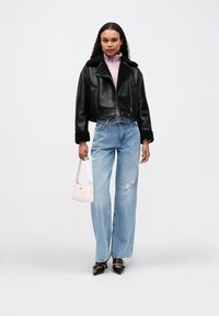 Μαύρο κομμένο δερμάτινο μπουφάν με γούνα στο γιακά, ροζ πουλόβερ, ανοιχτό γαλάζιο τζιν με σκισίματα και μια μικρή λευκή τσάντα. Μαύρες γόβες.