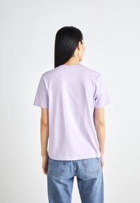 Lila kortärmad t-shirt i mjuk bomull med rund halsringning och avslappnad passform, i kombination med ljusblå jeans.