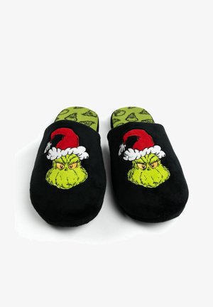 Black fabric slippers with plush texture, featuring a green Grinch face and red Santa hat design; green insole with small Grinch patterns.