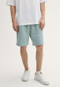 Lichtblauwe katoen shorts met een elastische taille, voorzien van zijzakken en omgeslagen/zijde zomen, gecombineerd met witte sneakers. Witte oversized t-shirt.