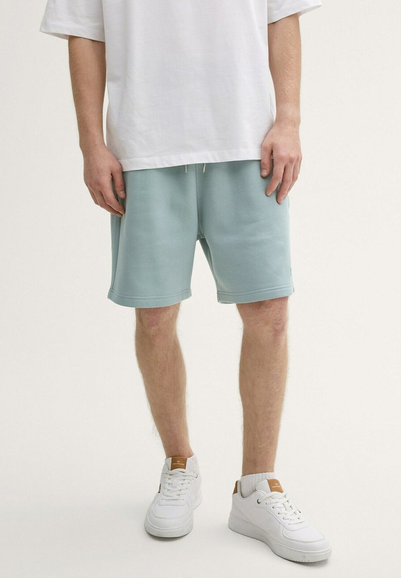Lichtblauwe katoen shorts met een elastische taille, voorzien van zijzakken en omgeslagen/zijde zomen, gecombineerd met witte sneakers. Witte oversized t-shirt.