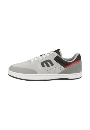 Gray athletic shoe with suede and leather material, white laces, black and red accents, perforated design, and a rubber sole.
