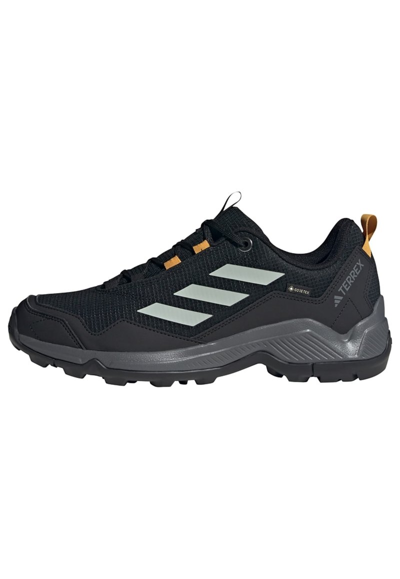 Zapatillas deportivas negras con parte superior de malla texturizada, suela de goma gris y acentos reflectantes. Cuentan con Gore-Tex para resistencia al agua.