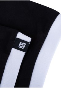 Schwarz-weißes Sportgewebe mit einem Logosticker, glatte Textur, mit deutlich kontrastierenden Farben und einem eleganten Design.
