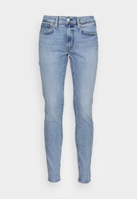 Jeans ajustados de color azul claro, hechos de mezclilla, con una cinturilla alta, diseño estándar de cinco bolsillos, cierre de botón metálico y sutiles detalles de desteñido.