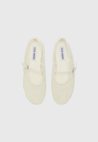 Chaussures de style Mary Jane blanches en mesh avec une bride, une tige texturée et un bout rond, dotées d'une doublure intérieure lisse et d'un logo de marque imprimé.