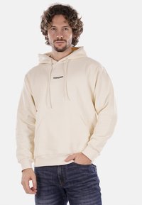 Felpa beiges realizzata in tessuto morbido con tasca a marsupio e cappuccio con coulisse. Presenta il testo "PROPAGANDA" in nero sul petto.