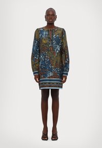 Geprinte jurk met lange mouwen, een ronde halslijn met strikdetails, en een mix van blauwe, oranje en witte bloem- en abstracte patronen.