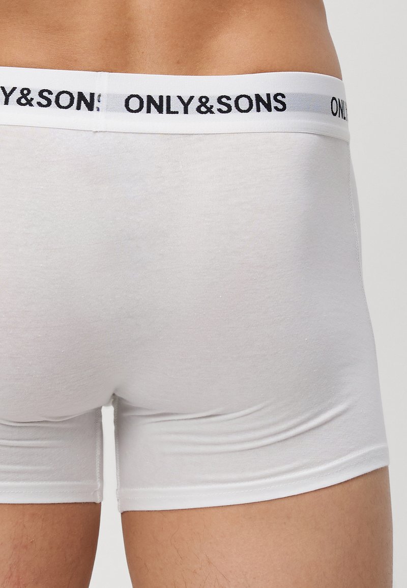 Vista posteriore di una persona che indossa boxer bianchi con una vita bianca con il testo nero "ONLY&SONS".