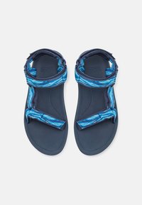 Blå mønstrede sandaler med en mørkeblå sål, som har et teksturert stroppdesign og justerbare lukninger for en sikker passform.