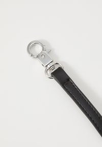 Correa de cuero negro con un brillante cierre metálico plateado. Presenta una textura suave y líneas limpias, destacando el diseño elegante.
