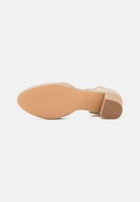 Glittering gold heeled shoe with a smooth, tan sole. Features a rounded toe and a low block heel for stability.