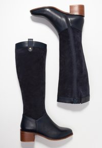 Marinblå höga stövlar med en kombination av slät läder och mocka. Rund tå, staplad träklack, dragkedja bak och ton-i-ton sömnadsdetaljer.