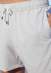 Helle graue Badeshorts aus strukturiertem Stoff mit elastischem Bund, Kordelzug und seitlichen Taschen.