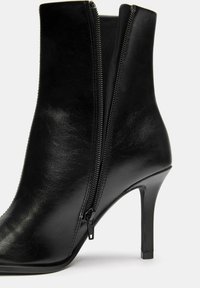 Stivaletto in pelle nera con punta affusolata, tacco a stiletto alto e doppia cerniera sul lato esterno per la chiusura. Texture liscia.