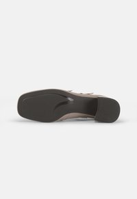Chaussure à talons marron avec un dessus en cuir lisse, un bout arrondi et une semelle en caoutchouc texturé ; design minimaliste et lignes épurées.