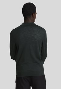 Dunkelgrüner Strickpullover mit langen Ärmeln und Kragen, der ein dezentes strukturiertes Muster und einen gerippten Saum aufweist. Rückansicht dargestellt.