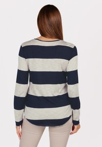 Maglietta a maniche lunghe con righe orizzontali blu navy e grigio chiaro. Tessuto morbido, scollatura tonda, orlo curvo e maniche aderenti.