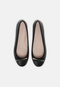 Bailarinas de cuero negro con puntera redondeada, que presentan un pequeño lazo acentuado en dorado en la parte delantera y una plantilla suave de color beige.