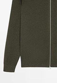 Dark green knit sweater with a full zipper, ribbed texture on sleeves and hem, and a smooth main body structure.