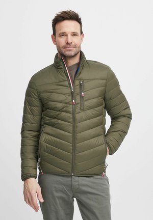 Olivegrüner gepolsterter Mantel mit hohem Kragen, diagonaler Steppnaht und kontrastierenden Reißverschlüssen. Seitentaschen sorgen für Funktionalität.
