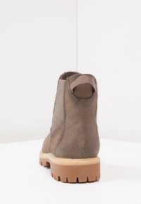 Braune Leder-Stiefel mit elastischen seitlichen Einsätzen, strukturierten Oberflächen und einer robusten Gummisohle mit tiefen Profilen für besseren Halt.