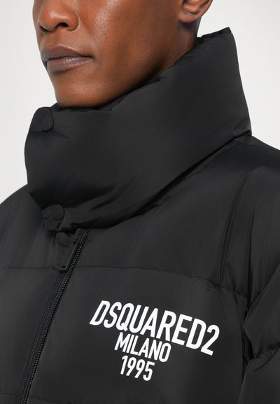Zwarte pufferjack met hoge kraag, voorzien van witte bedrukte tekst "DSQUARED2 MILANO 1995" en knoopsluitingen op de kraag. Gladde textuur.